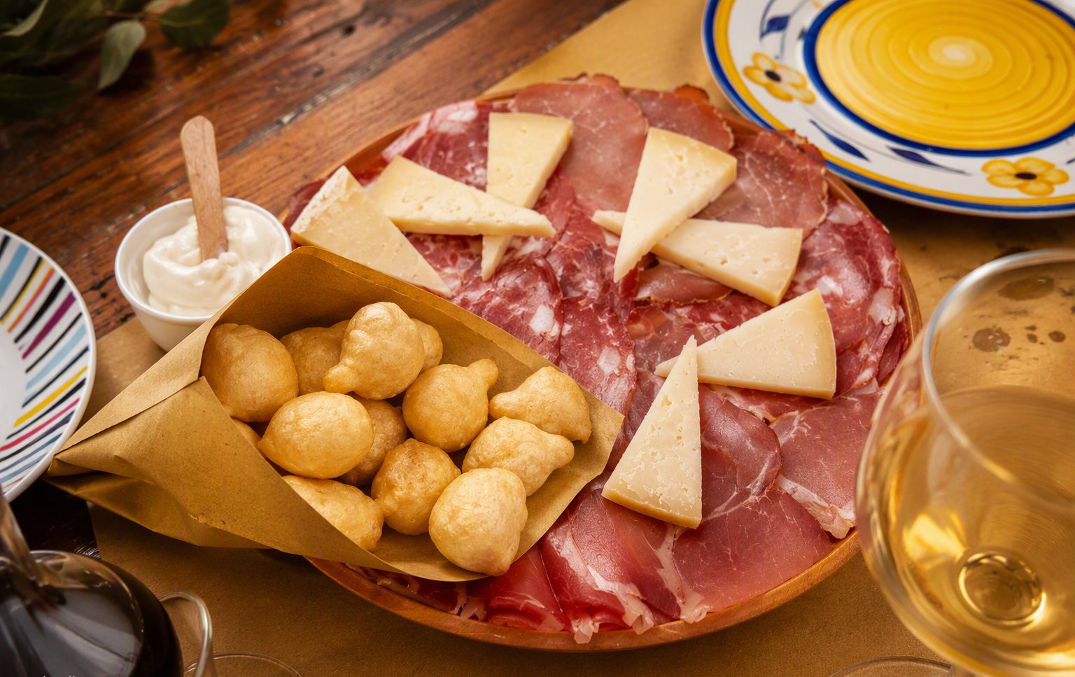 Il tagliere con prosciutto, pecorino e i coccoli dorati nel cono di carta